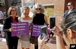Oregon Gov. Kate Brown, left, poses for photos with supporters after a rally in Portland, Ore., Oct. 17, 2018. A measure to ban the use of state funds to pay for abortions is on the ballot in Oregon, the state with the least restrictive abortion laws in the nation.