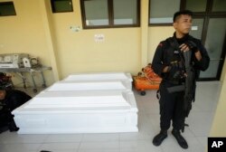 Seorang petugas polisi berjaga-jaga dekat peti mati yang dipersiapkan untuk korban serangan gereja di sebuah rumah sakit di Surabaya, Indonesia, Senin, 14 Mei 2018. (Foto: dok).