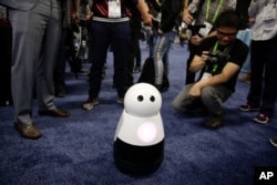Mayfield Robotics' Kuri home robot is surrounded by attendees during CES Unveiled at CES International Sunday, Jan. 7, 2018, in Las Vegas. (AP Photo/Jae C. Hong)