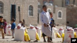 FILE - A displaced boy who fled Saada province, northwest of Sana'a with his family, waits for relief supplies during a food distribution by Yemeni volunteers in Sanaa, Yemen, Dec. 17, 2015.