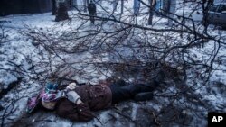 FILE - A person walks near the body of a man lying near a bus stop that was damaged in shelling in Donetsk, eastern Ukraine, Jan. 20, 2015. An estimated 9,000 people have died in the conflict in eastern Ukraine since April of 2014.