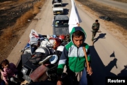 An Iraqi displaced child holds white flag as he is fleeing with his family during a battle with Islamic State militants in Kokjali village near Mosul, Iraq, Nov. 03, 2016.