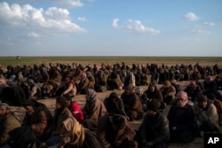 Men wait to be screened by U.S.-backed Syrian Democratic Forces fighters after being evacuated out of the last territory held by Islamic State militants, near Baghuz, eastern Syria, Feb. 22, 2019.