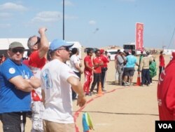 Audience members watch skydivers jump from a helicopter during a skydiving competition in Egypt. More than 200 skydivers from 17 countries are participating in the 3-day competition, March 2, 2016. (H. Elrasam/VOA)