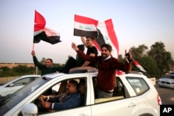 Iraqis wave national flags, celebrating the anniversary of the victory over the Islamic State group, in the so-called Green Zone in Baghdad, Iraq, Monday, Dec. 10, 2018. (AP Photo/Karim Kadim)