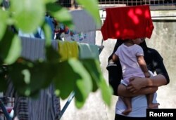 FILE - A Rohingya child bride who ran away from her husband carries her sister outside a shack she shares with her mother and siblings, on the outskirts of Kuala Lumpur, Malaysia, Feb. 9, 2017.