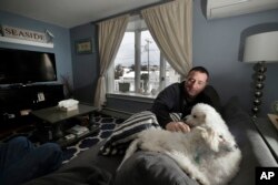 Denis Champagne, Jr. plays with his dogs Maebelle and Isabel at home near the coast in Salisbury, Mass., Jan. 23, 2019.