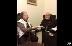 FILE - This Feb. 3, 2018 photo shows Marie Collins, a member of the Pope Francis' sex-abuse commission, hands a letter to Cardinal Sean O'Malley detailing the abuse of Juan Carlos Cruz and a cover-up by Chilean church authorities, at the Domus Santa Marta, at the Vatican on April 12, 2015.