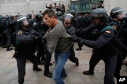 Civil guards clear people away from the entrance of a sports center, assigned to be a polling station by the Catalan government and where Catalan President Carles Puigdemont is expected to vote, in Sant Julia de Ramis, near Girona, Spain.