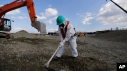A worker, wearing a protective suit and a mask, levels ground at the tsunami-crippled Fukushima Dai-ichi nuclear power plant, operated by Tokyo Electric Power Co. (TEPCO), in Okuma, Fukushima Prefecture, northeastern Japan, Wednesday, Feb. 10, 2016.
