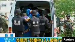 FILE - Riot policemen lead men who are about to be executed into a police van in an unknown location in the Xinjiang Uighur Autonomous Region.