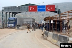 FILE - Syrians wait at a checkpoint at the Syrian border crossing of Bab al-Hawa on the Syrian-Turkish border in Idlib Governorate, Jan. 21, 2015.
