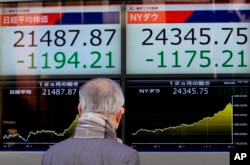 A man looks at an electronic stock indicator of a securities firm in Tokyo, Japan, Feb. 6, 2018.
