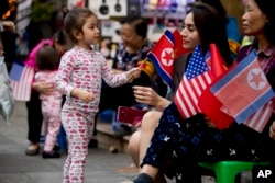A girl plays with American, North Korean, and Vietnamese flags in a tourist area near Sword Lake in Hanoi, Vietnam, Feb. 27, 2019.