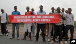 Young men hold a banner along a road taken by a U.N. Security Council convoy in Bujumbura, Burundi, Jan. 21, 2016.