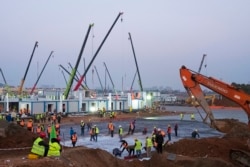 Construction workers labor at the site of the Huoshenshan temporary field hospital being built in Wuhan in central China's Hubei Province, Thursday, Jan. 30, 2020. (AP Photo/Arek Rataj)