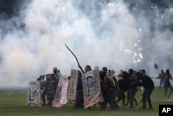 Protesters shield themselves as police fire tear gas during their demonstration outside Congress in Brasilia, Brazil, Tuesday, Nov. 29, 2016.
