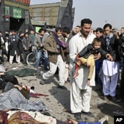 A man carries a wounded boy after a suicide blast targeting a Shi'ite Muslim gathering in Kabul, December 6, 2011