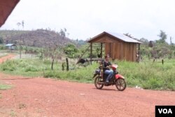 អ្នកភូមិ​ម្នាក់​បើក​ម៉ូតូ​កាត់ផ្លូវ​មួយ​ក្នុង​ឃុំ​អូរសោម ដែល​អ្នកភូមិ​និយាយ​ថា ជនជាតិ​ចិន​កំពុង​ស្រាវជ្រាវ ដើម្បី​ស្ថាបនា​ផ្លូវ​តភ្ជាប់​ទៅ​ខេត្តកោះកុង និង​បាត់ដំបង នា​ពេល​ខាងមុខ។ (ស៊ុន ណារិន/VOA)