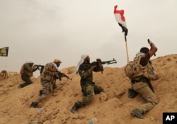 FILE - Fighters from Badr Brigades Shiite militia clash with Islamic State group militants at the front line on the outskirts of Fallujah, Anbar province, Iraq, June 1, 2015.