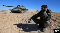 FILE - A member of the Syrian pro-government forces speaks on a mobile phone as troops gather on a hilltop overlooking the town of Mahin, which is under control of the Islamic State group, in Homs province, Nov. 14, 2015.