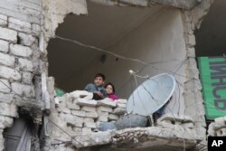 FILE - Children peer from a partially destroyed home in Aleppo, Syria, Feb. 11, 2016.