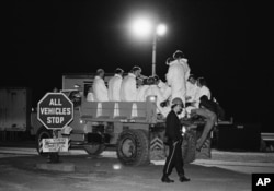 The night crew at Three Mile Island nuclear power plant wear protective clothing as they sit in the back of a truck that transported them to the shutdown power plant in Harrisburg, Pa., March 29, 1977 at the beginning of their shift.