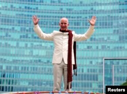 Jeff Bezos, founder and chief executive officer of Amazon, poses as he stands atop a supply truck during a photo opportunity at the premises of a shopping mall in the southern Indian city of Bangalore September 28, 2014.