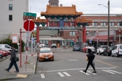 Pedestrians walk near the main entrance to Seattle's Chinatown-International District Thursday, March 18, 2021. (AP Photo/Ted S. Warren)