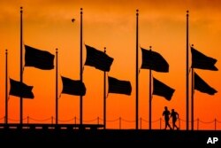 Runners pass under the the flags flying at half-staff around the Washington Monument at daybreak in Washington, Monday, June 13, 2016. The flags were ordered to half-staff by President Barack Obama to honor the victims of the Orlando nightclub shootings.