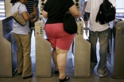 FILE: An overweight woman walks through a turnstyle. Half of Americans will be obese by 2030, says a new study.