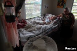 Carmen Rodrigues stands by her bedridden mother, Rosa Maria Torres, 95, after Hurricane Maria destroyed the town's bridge in San Lorenzo, Morovis, Puerto Rico, Oct. 5, 2017.