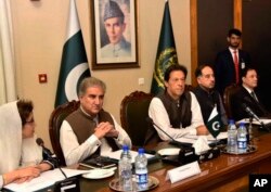 FILE - In this photo released by the Press Information Department, Pakistani Prime Minister Imran Khan, center, attends a briefing at the Foreign Ministry in Islamabad, Pakistan, Aug. 24, 2018.