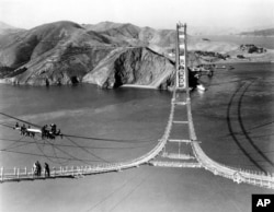 Workers complete the catwalks for the Golden Gate Bridge, spanning the Golden Gate Strait, prior to spinning the bridge cables during construction in San Francisco, California, October 25, 1935. (AP Photo)