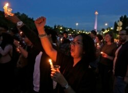 Seorang aktivis memegang lilin dan meneriakkan slogan-slogan saat berjaga untuk seorang gadis remaja yang diperkosa dan dibunuh oleh 14 pria di Bengkulu, di luar istana presiden di Jakarta. (Foto: AP)