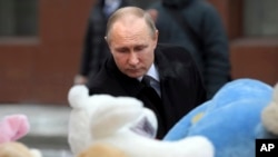 Russian President Vladimir Putin lays flowers at a memorial made for the victims of a fire in a multi-story shopping center in the Siberian city of Kemerovo, about 3,000 kilometers (1,900 miles) east of Moscow, Russia, Tuesday, March 27, 2018.