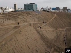 FILE - Tourists walk the trails of the pre-Columbian archeological site Pucllana, surrounded by modern high-rises in the Miraflores district of Lima, Peru, Oct. 6 2017.
