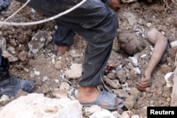 Men uncover a body from under debris after airstrikes in the rebel-held Karam Houmid neighborhood in Aleppo, Syria, Oct. 4, 2016.
