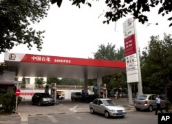 FILE - Motorist pump fuel at a Sinopec gas station in Beijing, China, Aug. 29, 2011.