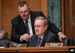 Senate Banking Committee Chairman Mike Crapo, R-Idaho, center, joined at left by Sen. Jon Tester, D-Mont., listens during a hearing on U.S. economic sanctions against Russia and whether the actions are effective, on Capitol Hill, Aug. 21, 2018.