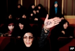 An Iranian raises her palm bearing Persian that reads, "I'm ready to sacrifice myself for the supreme leader," in Tehran, Feb. 24, 2016. During election campaigns and to humiliate reformists, hard-liners have accused their reformist rivals of being backed by the British government.