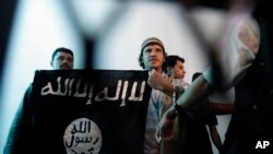 Seorang militan Al-Qaeda Yaman (tengah) menunjukkan spanduk saat persidangan terkait keamanan negara di Sanaa, Yaman, 23 April 2013. (Foto: Hani Mohammed/AP Photo)