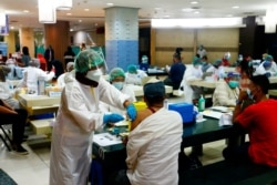 Seorang pedagang menerima dosis vaksin Sinovac Biotech China untuk COVID-19 di Pasar Tanah Abang, 17 Februari 2021. (Foto: REUTERS/Ajeng Dinar Ulfiana)