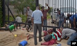 Student protesters seeking refuge crawl under the gates of the U.S. Embassy in the capital Bujumbura, Burundi, June 25, 2015.