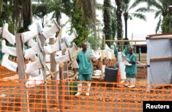 FILE - Congolese health workers clean gumboots as they prepare the Ebola treatment center in the village of Mangina in North Kivu province of the Democratic Republic of Congo, Aug. 18, 2018.