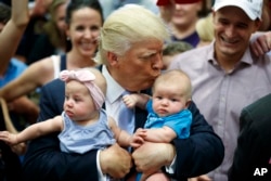 Republican presidential candidate Donald Trump kisses Kellen Campbell of Denver while also holding Evelyn Keane of Castle Rock, Colo., during a campaign rally in Colorado Springs, Colo., July 29, 2016.