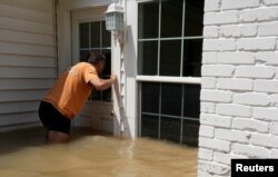 Patrice Laporte looks to see how much water is in his house surrounded by Harvey floodwaters in Houston, Texas, Sept. 1, 2017.