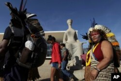 Indians walk past a statue of justice as they protest outside the Supreme Court, in Brasilia, Brazil, Aug. 16, 2017. Brazil's indigenous communities protested as the Supreme Court deliberated on the legality of President Michel Temer's plan to restrict land titles awarded to the communities.