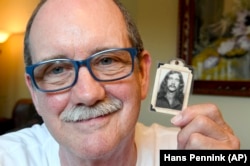 Kevin Rheden poses for a photograph with a photo of himself taken while in high school as he talks about his memories of the original Woodstock music festival in Bethel, New York.