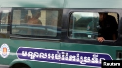 Uon Chhin and Yeang Sothearin, former journalists of the Radio Free Asia (RFA), sit inside a police vehicle as they arrive for a bail hearing at the Appeal Court in Phnom Penh, Cambodia, April 19, 2018.